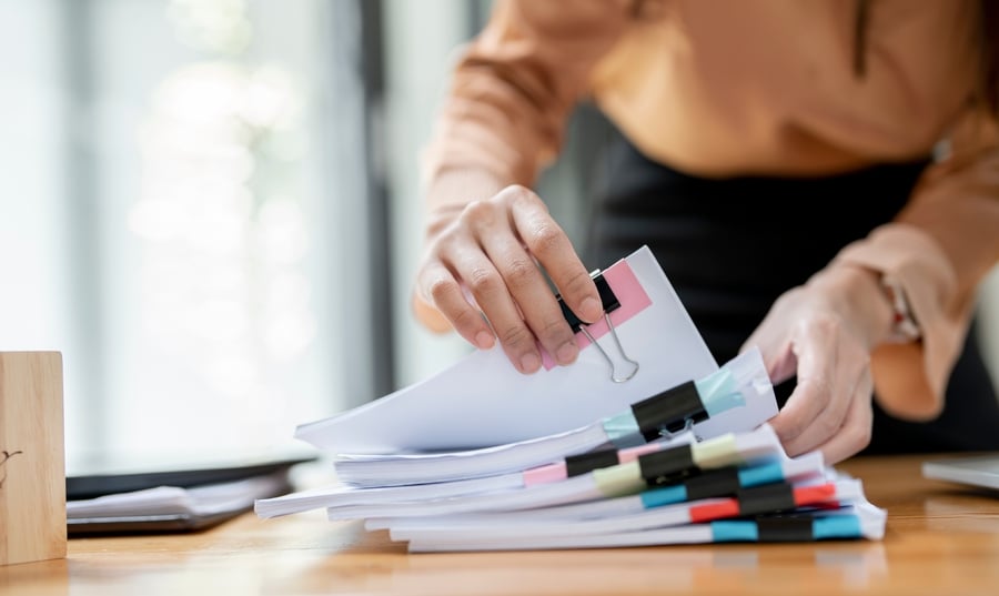 Women Scanning Through Stack of Papers 